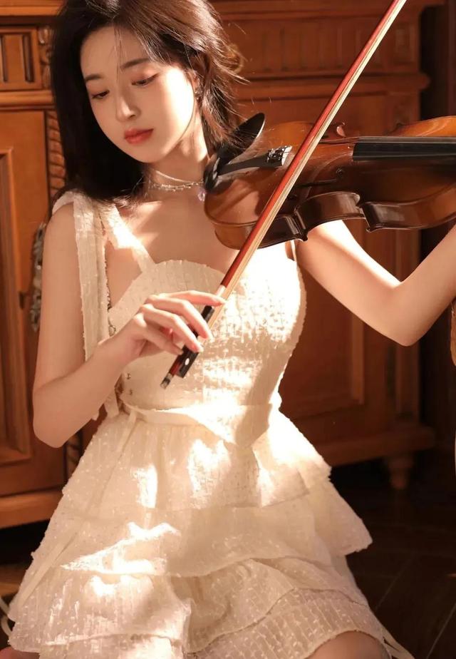 穿着可甜可盐白色吊带蛋糕裙的小提琴女孩